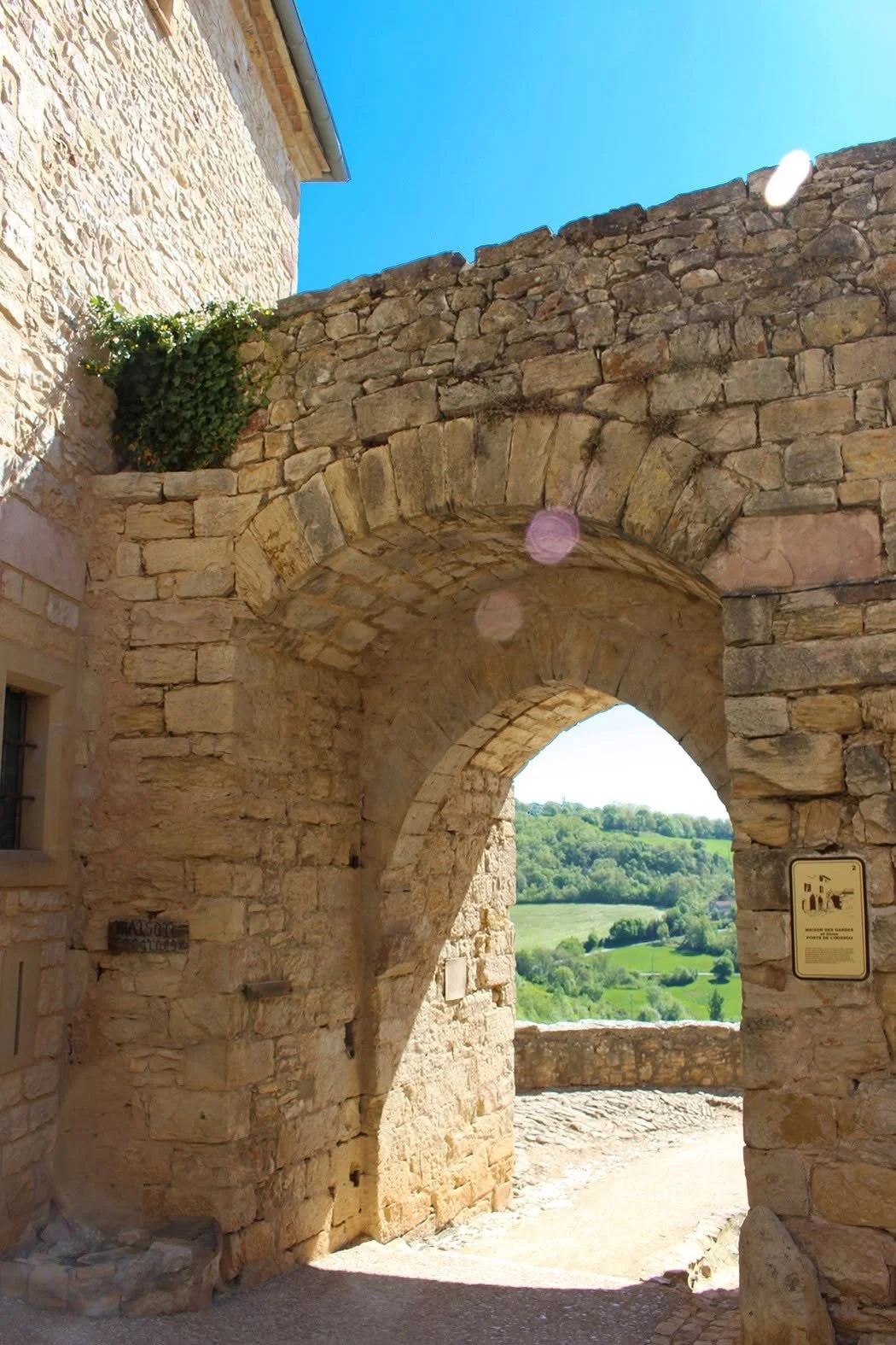 An ancient stone archway in the village walls, opening onto green hills