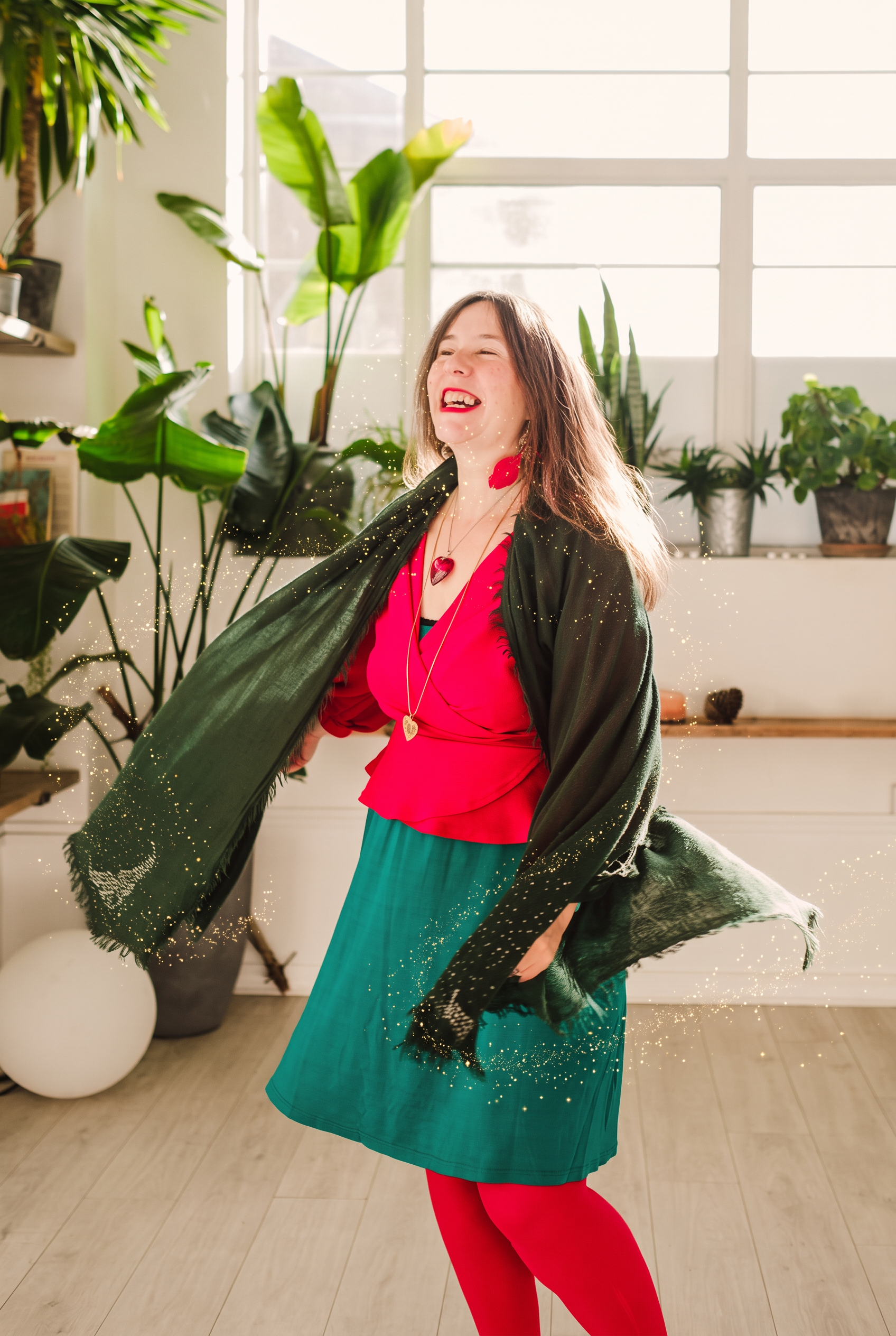 Emily laughing and twirling in a green scarf with golden stardust around her