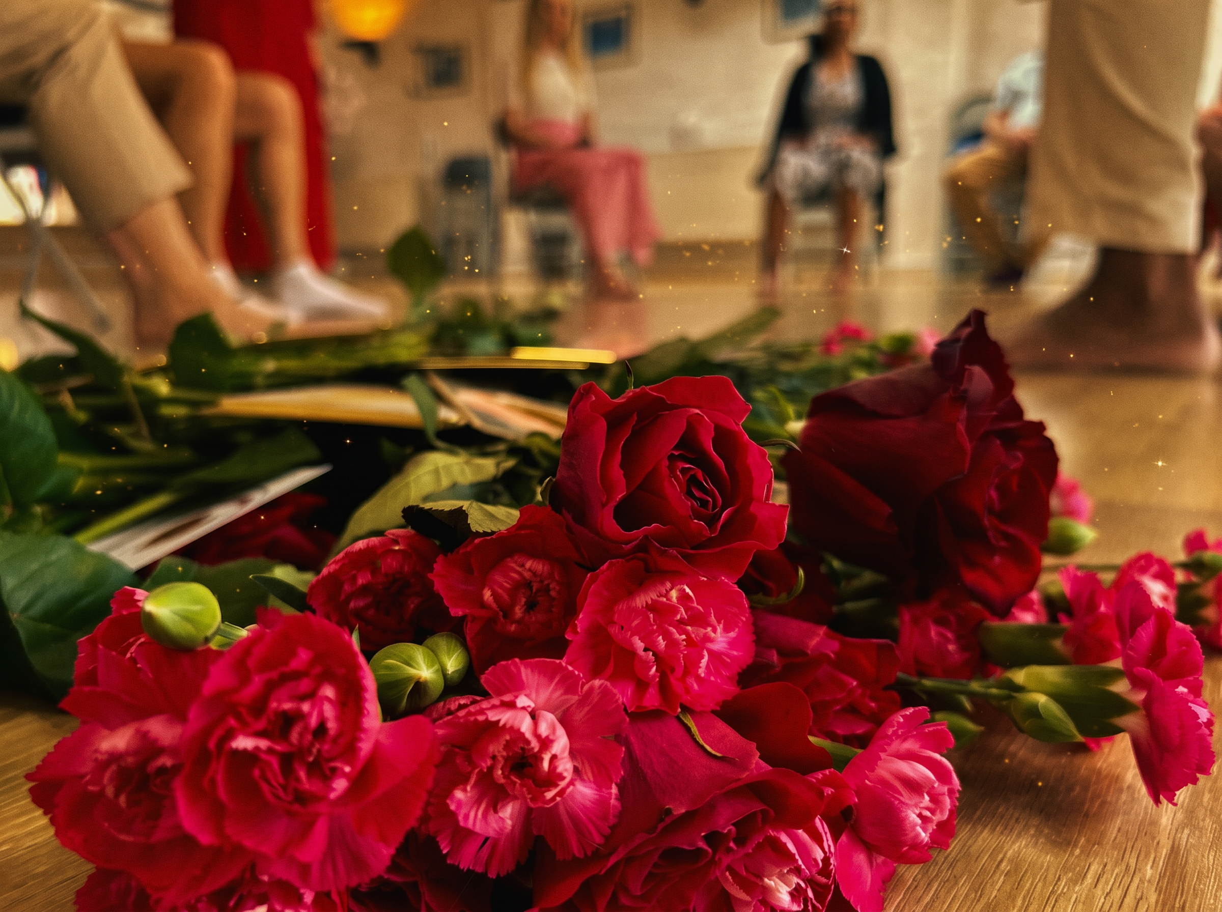 Red roses and carnations on the floor in front of a circle of guests